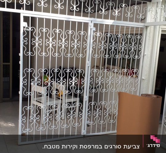 רול נייר חום עומד על מרפסת ליד סורג לבן